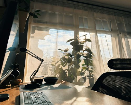 An organized and ergonomic home office setup with natural lighting and a water glass